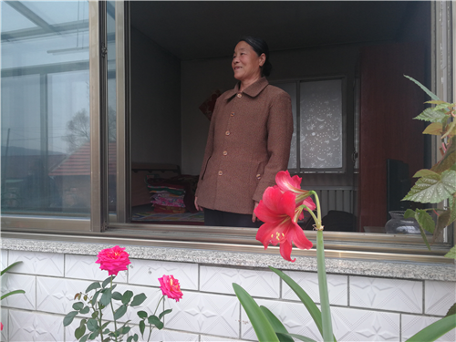 永陵鎮(zhèn)頭道堡村村民站在整潔美麗的家中，說起環(huán)境的變化，笑了。.png